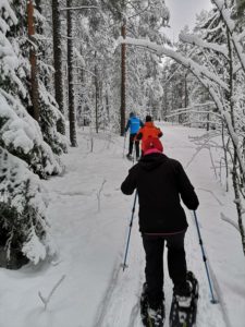 ihmiset lumikenkäilemässä