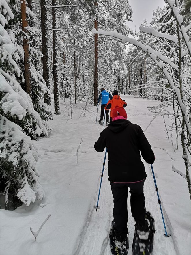 ihmiset lumikenkäilemässä